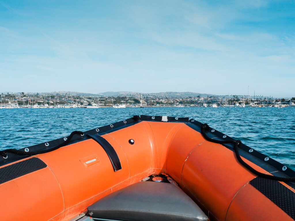 Point of view from inside a bright orange zodiac boat, heading towards the coast of Southern California