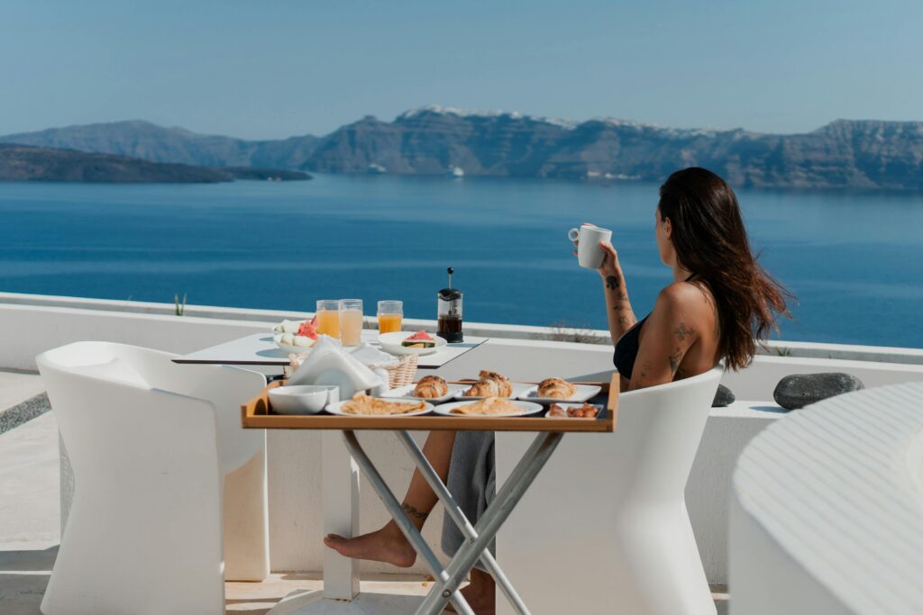Woman eating breakfast on rooftop with ocean view in Santorini, Greece