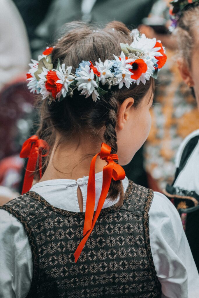 Young girl in a folk dress and flower wreath, representing French cultural traditions.