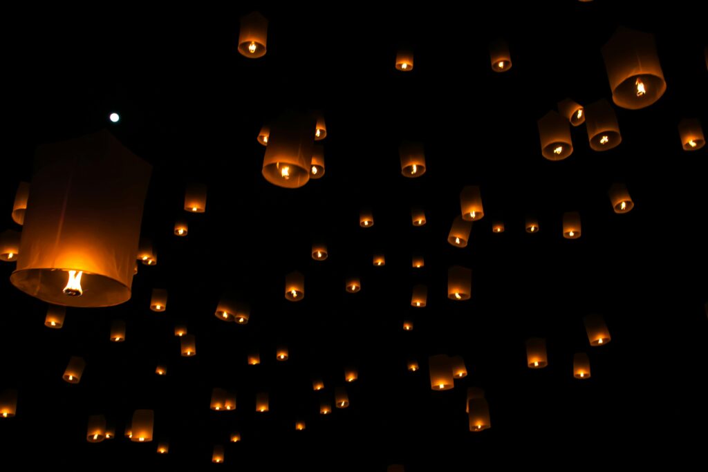 Lanterns glowing and floating into the night sky under a full moon during the Asian Moon Festival, symbolizing unity, hope, and celebration.